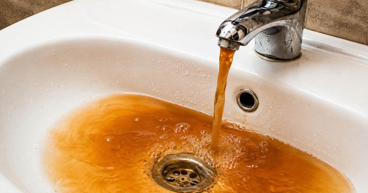 Rusty Water Flowing into White Sink